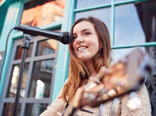 female-musician-busking-playing-acoustic-guitar-QGPZ2UP.jpg